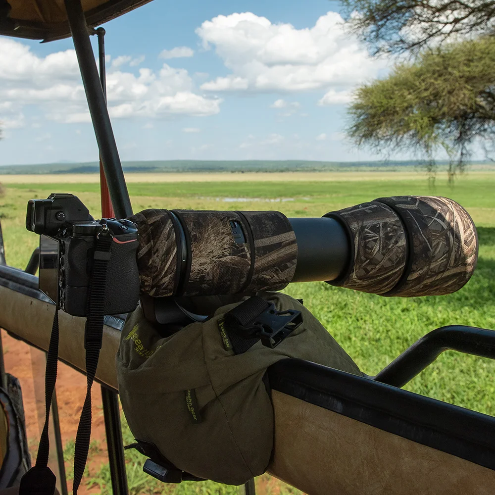 Photographer standing in an open safari vehicle with camera overlooking the plains