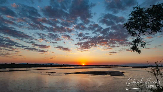 Sunset over the Rufiji River with glowing sky and calm water in Nyerere National Park, Tanzania.
