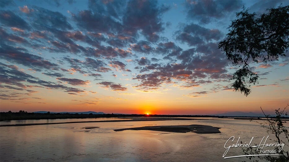 Sunset over the Rufiji River with glowing sky and calm water in Nyerere National Park, Tanzania.