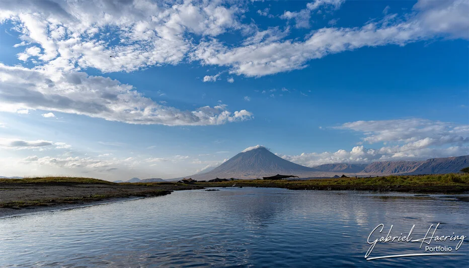 Ol Doinyo Lengai reflected in water at Lake Natron, volcanic landscape photography in Tanzania