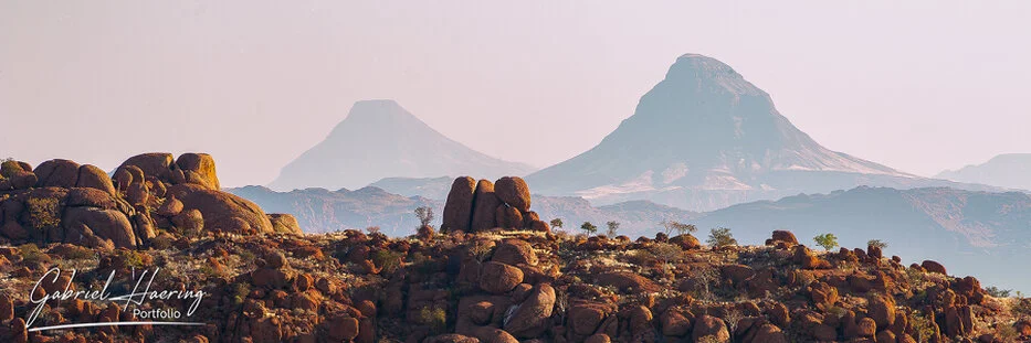 Layered Damaraland mountains and granite boulders fading into soft desert haze in Namibia