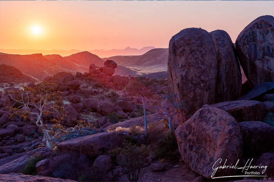 Warm sunset over rounded granite boulders and distant desert mountains in Damaraland, Namibia