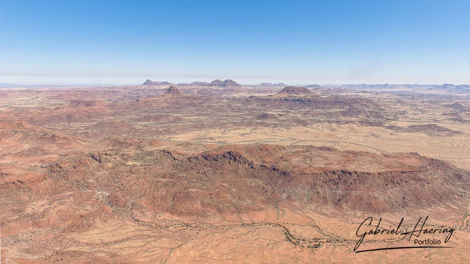 Wide aerial landscape of rugged mountains and arid plains in Damaraland, Namibia