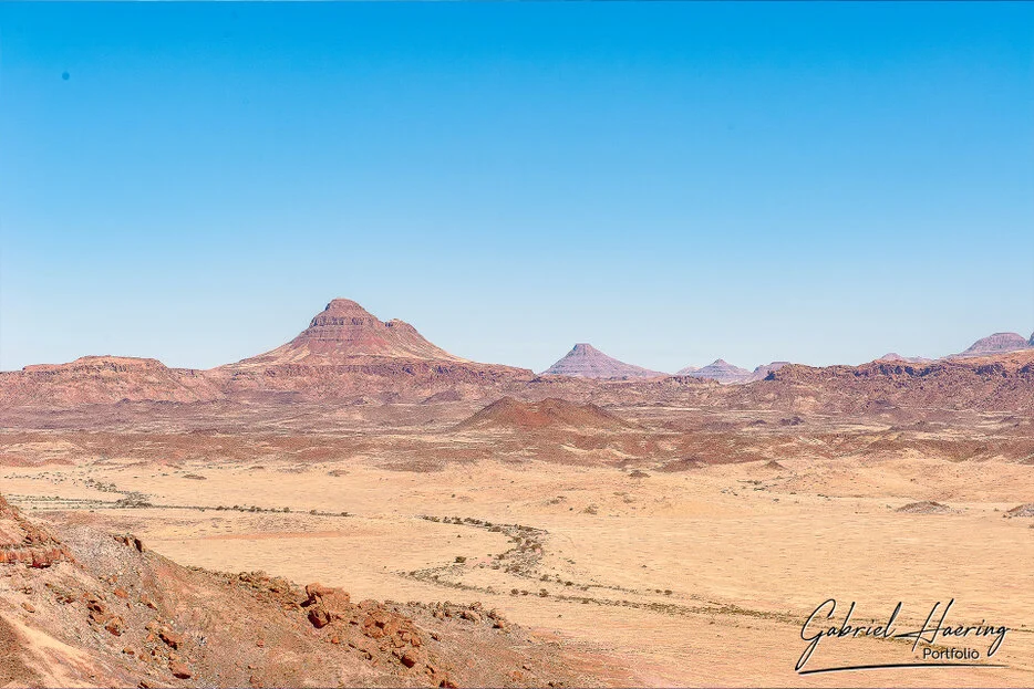Distant mesas and desert plains under a clear blue sky in Damaraland, Namibia