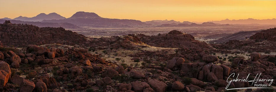 Sunset light over granite boulders, mountains and desert plains in Damaraland, Namibia