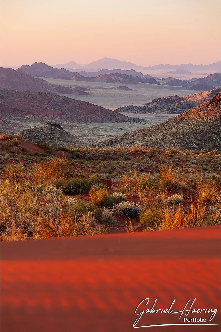 Layered mountain landscape with red dunes and desert grasses in the Namib-Naukluft region of Namibia